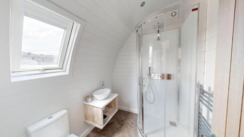 baño blanco con ducha y lavamanos en Byrnside Lodge, en Latheron