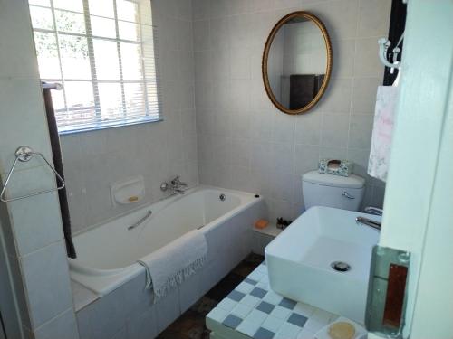 a bathroom with a tub and a toilet and a sink at Jan's Cottage in Centurion