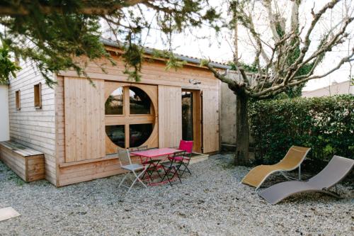Cabaña de madera pequeña con sillas y mesa en Charming Tiny House en LʼIsle-sur-la-Sorgue