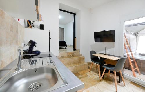 une cuisine avec un évier et une table avec des chaises dans l'établissement Nice Apartment In Jonquières-Saint-Vince, à Jonquières-et-Saint-Vincent