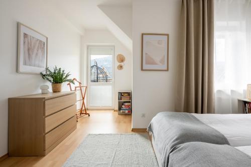 a bedroom with a bed and a dresser and a window at Giewont Mountain View Apartment in Zakopane