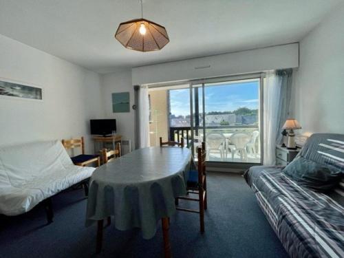 Cette chambre comprend une table, un lit et une fenêtre. dans l'établissement Appartement 2 pièces avec balcon, piscine et parking, à 1km de la plage - Animaux acceptés - FR-1-478-27, à Quiberon
