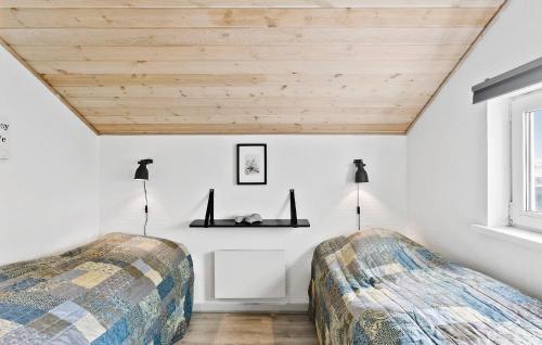ロッケンにあるAmazing Home In Lkken With 4 Bedrooms, Sauna And Wifiの白い壁と木製の天井が特徴のベッドルーム1室(ベッド2台付)
