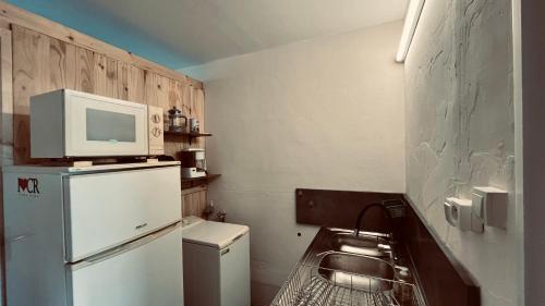 une petite cuisine avec un micro-ondes au-dessus d'un réfrigérateur dans l'établissement La Cabine de Plage chaleur & mer, à Saint-Jean-de-Monts