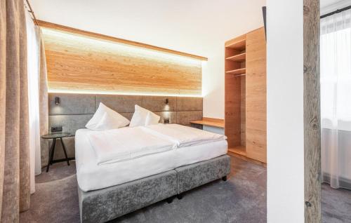 sypialnia z białym łóżkiem i drewnianą ścianą w obiekcie Stilvolle Ferienwohnung w mieście Sankt Anton am Arlberg