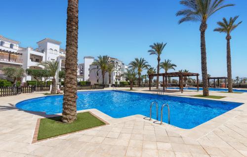 a swimming pool with palm trees and buildings at Awesome Apartment In Torre-Pacheco in Torre-Pacheco