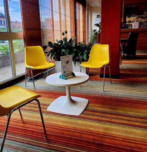 a group of chairs and a table with a book on it at The Originals City, Hôtel Le Forum, Strasbourg Nord in Schiltigheim