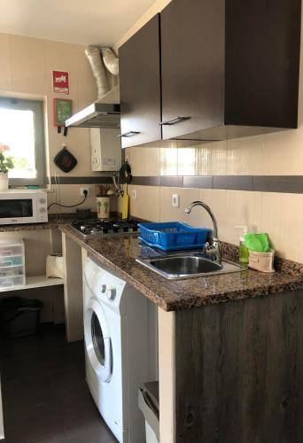 a kitchen with a sink and a washing machine at Casa da Avó Olinda in Góis