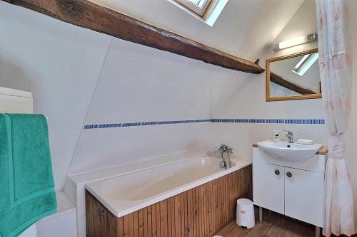 a bathroom with a bath tub and a sink at La petite maison bleue in Les Portes du Coglais