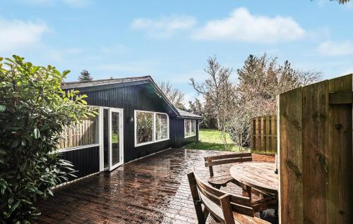 a black house with a wooden table and chairs at Four-Bedroom Holiday Home In Vaggerlose in Marielyst