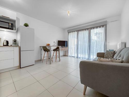 a living room with a couch and a kitchen at Vivez Lunel-Clim-Wifi Fibre-Parking Privé-Patio T2 in Lunel