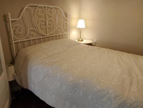 1 dormitorio con 1 cama con colcha blanca y lámpara en El Palacito de Arnedillo, en Arnedillo