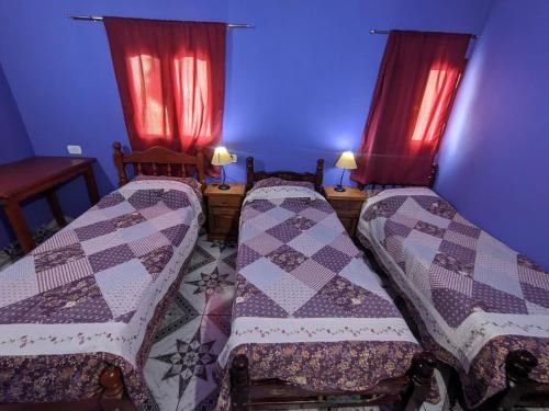 two beds in a room with red curtains at Hostal Mary in Iruya