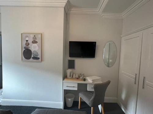 Habitación con escritorio y TV en la pared. en Alexander Hotel, en Whitley Bay