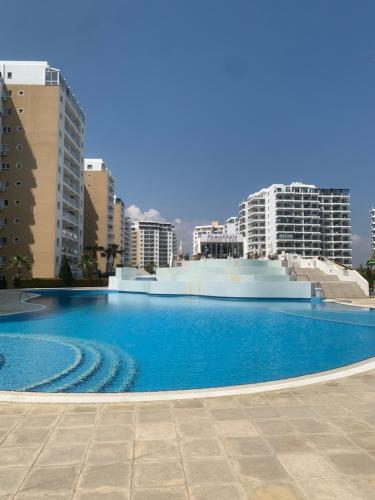 a large blue swimming pool with buildings in the background at Nice Flat in Caesar in Iskele