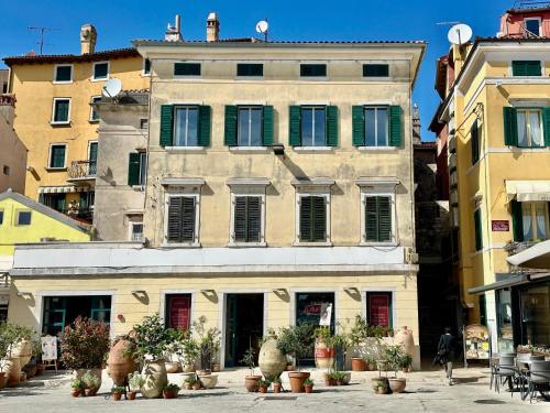 Un edificio antiguo con ventanas con contraventanas verdes en una ciudad. en Apollo Suite Rovinj, en Rovinj