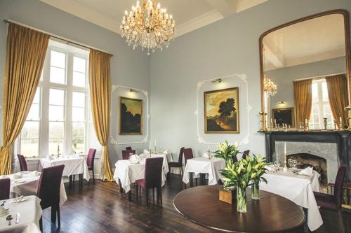 a dining room with white tables and chairs and a chandelier at Kinnitty Castle Hotel in Kinnitty