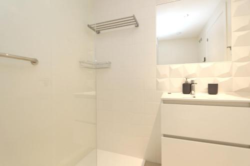 La salle de bains blanche est pourvue d'un lavabo et d'une douche. dans l'établissement Luxury Panorama Mar by Grupo Quattro, à Punta Prima