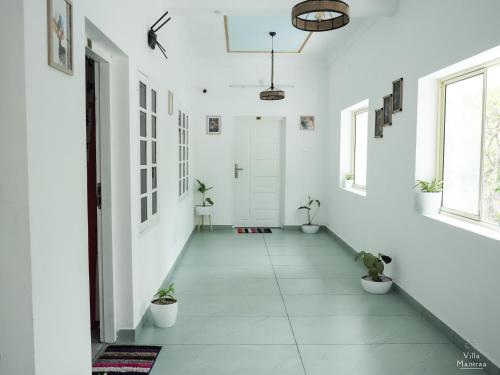 a hallway with white walls and potted plants at VILLA MANTRAA in Varkala