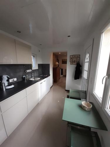 une cuisine avec des placards blancs et une table verte dans l'établissement La Clef des Champs, à Bruille-lez-Marchiennes