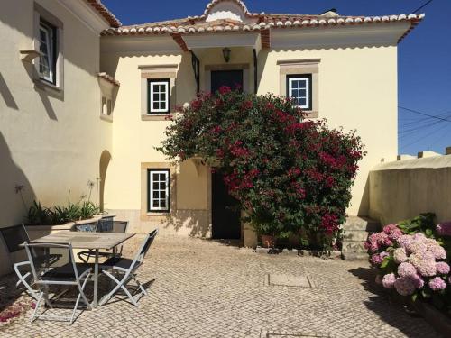 a table and chairs in front of a house with flowers at Casa do Mestre João in São Martinho
