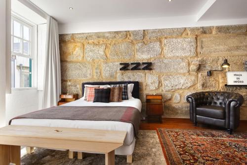 a bedroom with a bed and a stone wall at Oporto Chic & Cozy Studio Apartments in Porto