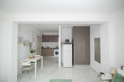 a white kitchen with a table and a white refrigerator at Quattro City Center Ap 501B in Larnaka