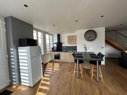 a kitchen with a table and a refrigerator at Gîte le C-47 in Sainte-Mère-Église