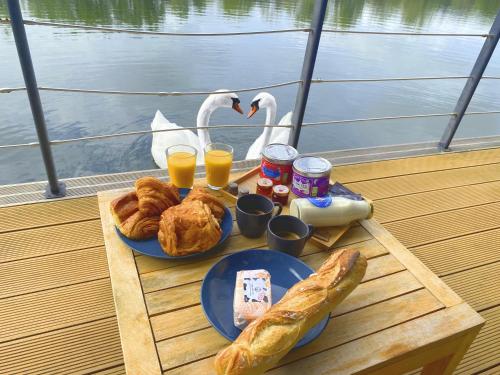 una mesa con pan, bebidas y cisnes en un barco en L'Escale Royale - Port de Saverne à 30' de Strasbourg en Saverne