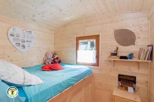 um pequeno quarto com uma cama num chalé de madeira em Gite les Ecureuils em Herbeys