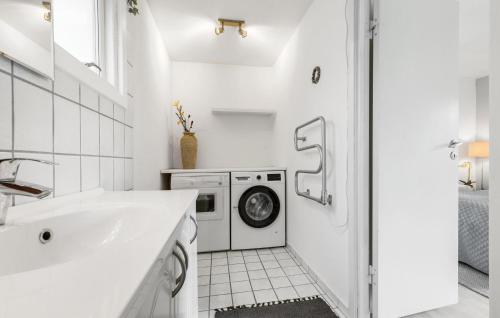 y baño blanco con lavabo y lavadora. en Lovely Home In Dronningmlle With Kitchen, en Dronningmølle