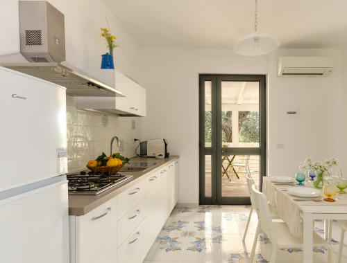 a kitchen with white cabinets and a table and a dining room at Le Case di Chri in Mattinata