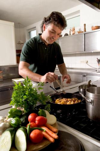 a man preparing food in a kitchen with vegetables at Bauer & Wirt Langthaler in Emmersdorf an der Donau