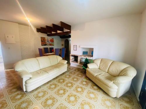two white leather couches in a living room at Chácara com Piscina e Amplo Quintal in Embu
