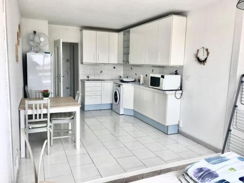 - une cuisine avec des placards blancs, une table et un réfrigérateur dans l'établissement Studio cabine vue mer centre port, au Cap d'Agde