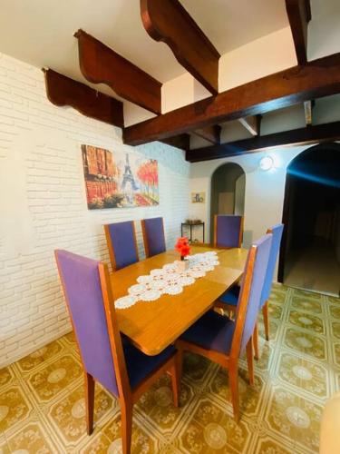 a dining room with a wooden table and blue chairs at Chácara com Piscina e Amplo Quintal in Embu
