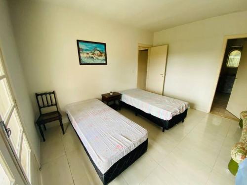 a room with two beds and a chair in it at Chácara com Piscina e Amplo Quintal in Embu