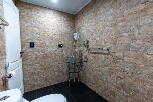 a bathroom with a toilet and a stone wall at Casa Vida in Sierra de los Padres
