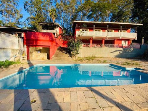 a blue swimming pool in front of a house at Chácara com Piscina e Amplo Quintal in Embu