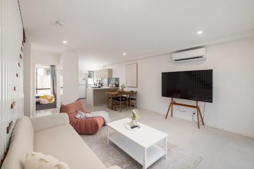 a living room with a white couch and a tv at Netflix Brand new 4BR Fast NBN AC Free Parking in Gold Coast