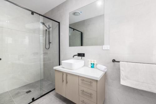 a white bathroom with a sink and a shower at Netflix Brand new 4BR Fast NBN AC Free Parking in Gold Coast