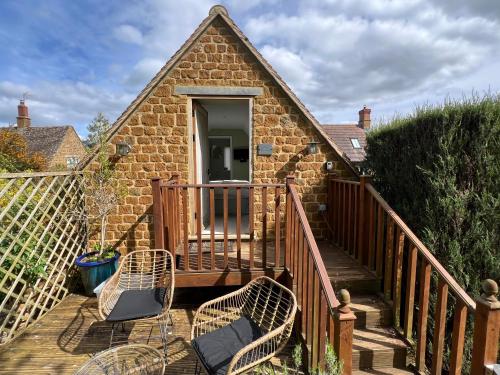a deck with two chairs and a building at Cotswold Retreat - Private & Peaceful in Horley