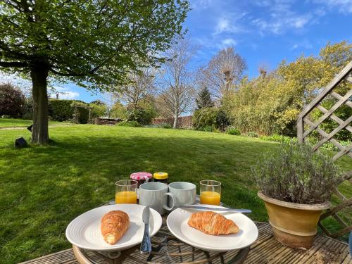 a table with two plates of croissants and orange juice at Cotswold Retreat - Private & Peaceful in Horley
