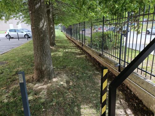 a black and yellow fence with a tree next to it at Studio Cosy neuf + lit bébé à 4 minutes RER A in Montévrain