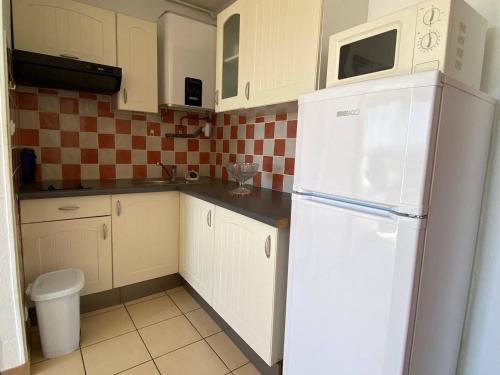 une cuisine avec des armoires blanches et un réfrigérateur blanc dans l'établissement Grand Studio 4 Pers avec Terrasse et Parking Privé au Barcarès - FR-1-81-485, au Barcarès