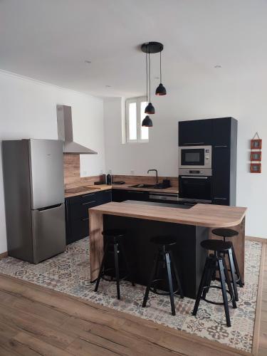 une cuisine avec un comptoir en bois et un îlot de cuisine avec des tabourets dans l'établissement Le Nid Tourbain, à Tourbes