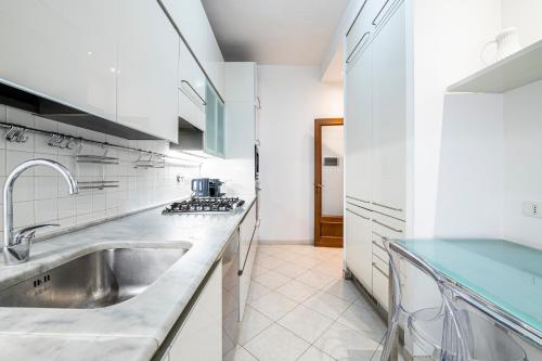 a white kitchen with a sink and a counter at [Lungarno] Casa esclusiva in Florence