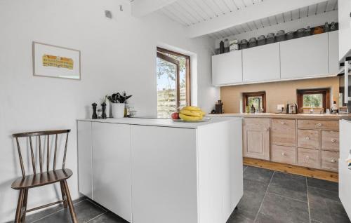 eine Küche mit weißen Schränken und einer Theke mit einem Stuhl in der Unterkunft 1 Bedroom Pet Friendly Home In Egå in Egå