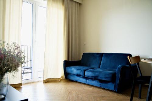 a blue couch in a living room with a window at Apartament Thaddeus 48 z tarasem in Zator