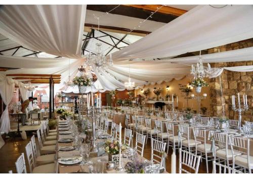 a banquet hall with white tables and chairs and chandeliers at Moolmanshoek Private Game Reserve in Fouriesburg